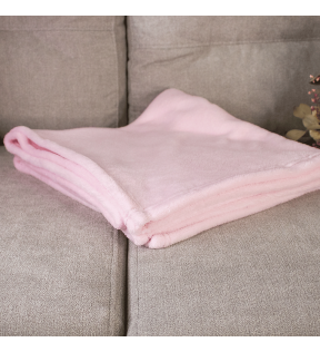 plaid polaire rose plié sur un canapé