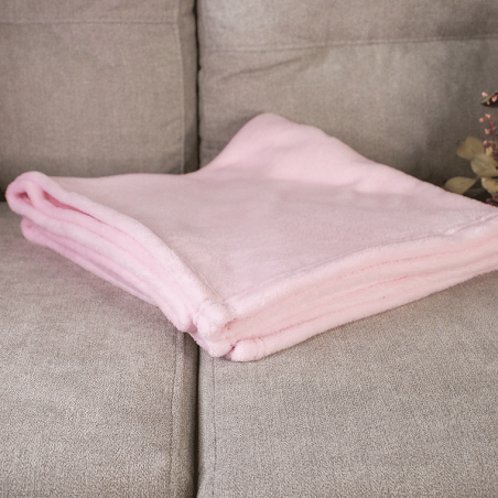 plaid polaire rose plié sur un canapé